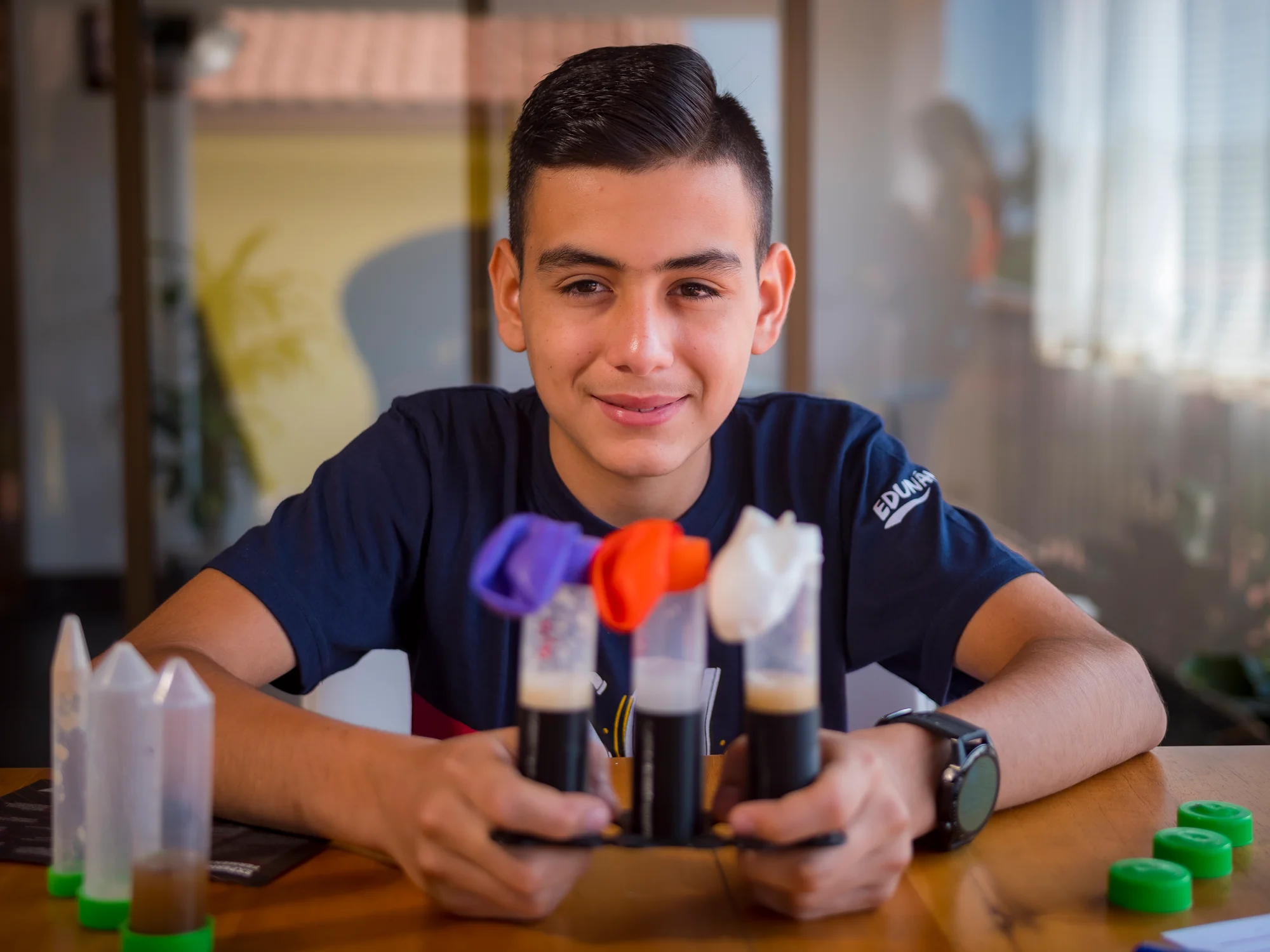 Edunámica beneficiary showing a homemade science experiment with test tubes and colored balloons
