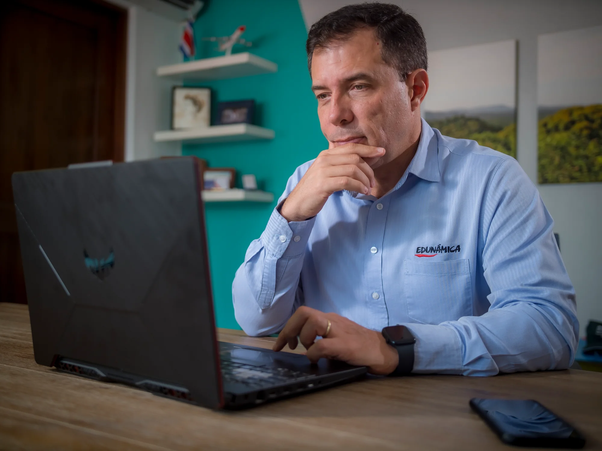 Institutional portrait of an Edunámica staff member wearing the organization's shirt, working on his laptop