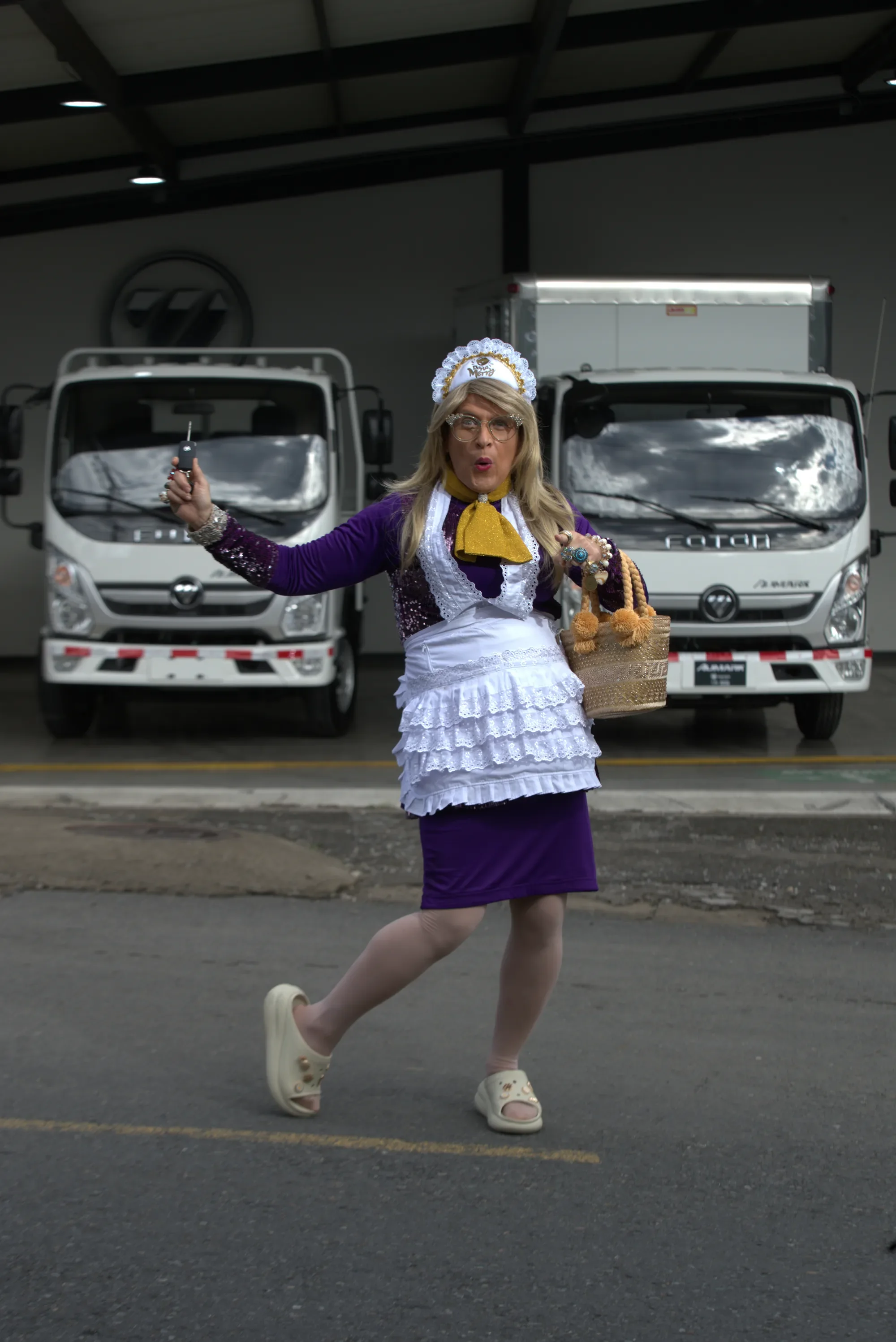 Doña Merry holds up the keys in front of two Foton Aumark trucks at the dealership